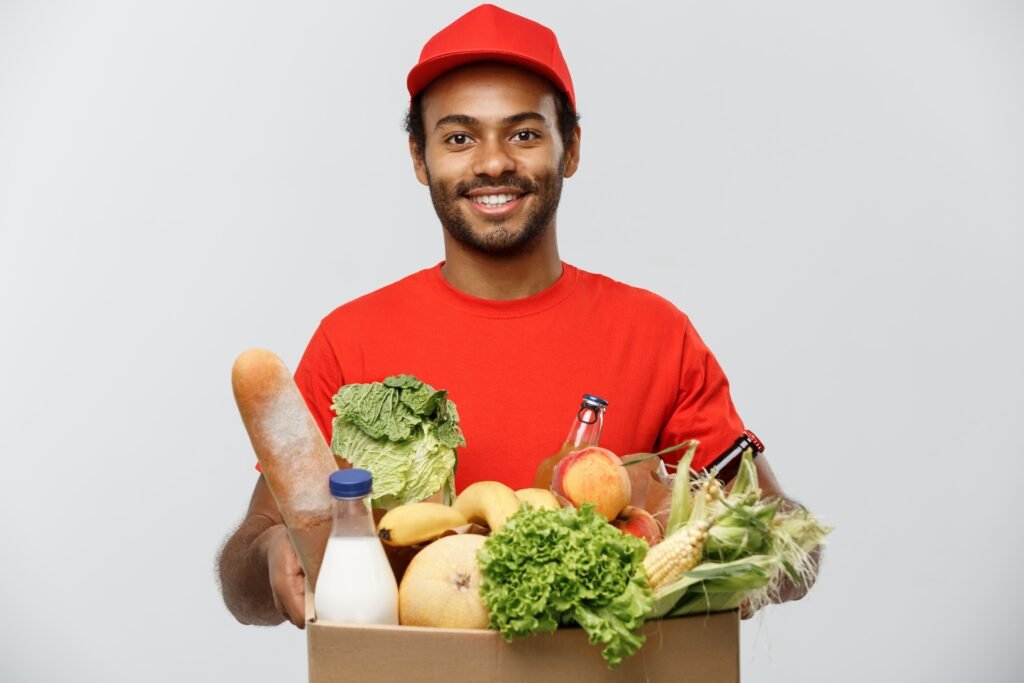 delivery concept handsome african american delivery man carrying package box grocery food drink from store isolated grey studio background copy space